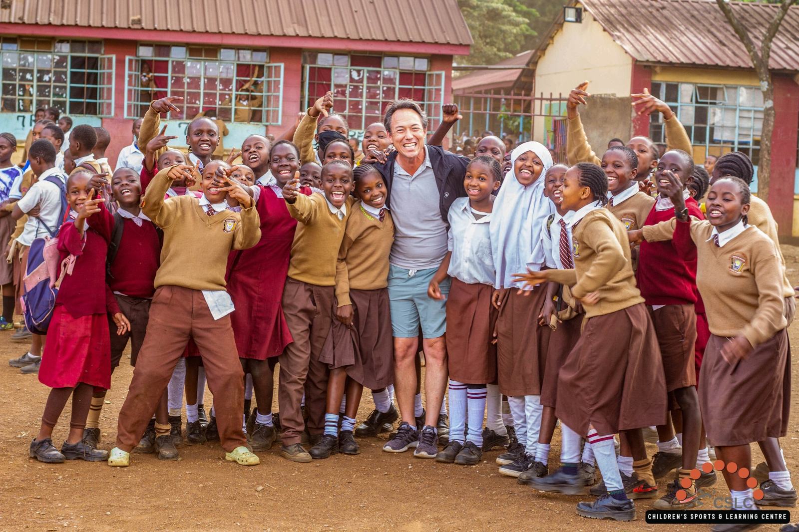 A large group of students celebrating with a Field of Hope visitor outside their school