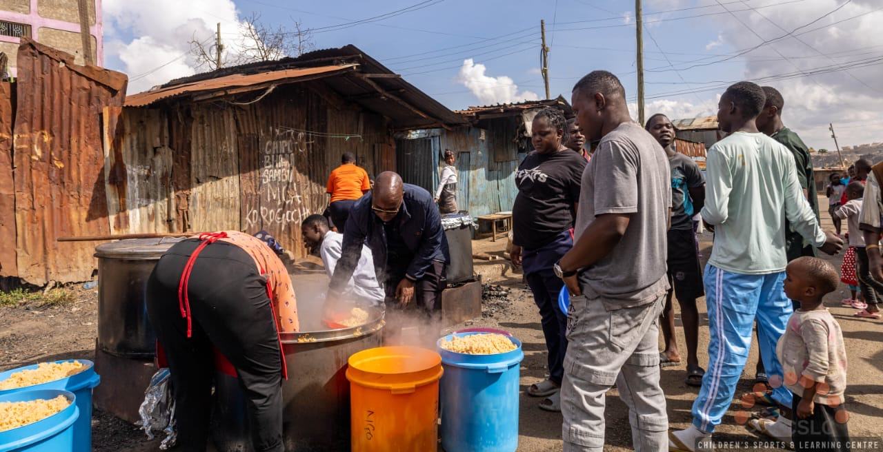 Community members cooking a large pot of food outdoors