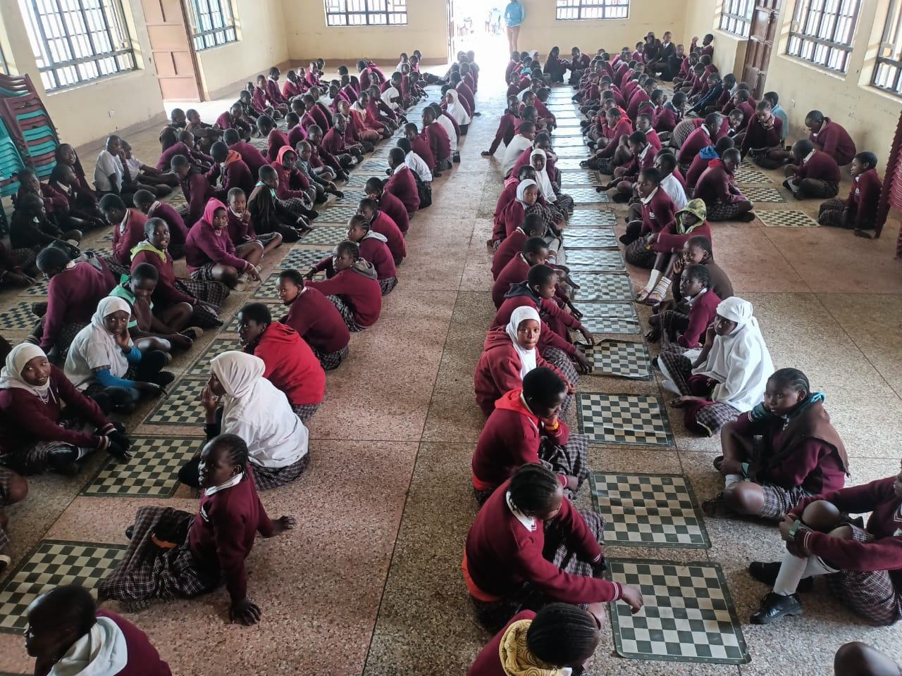 Rows of students playing chess together in a school hall