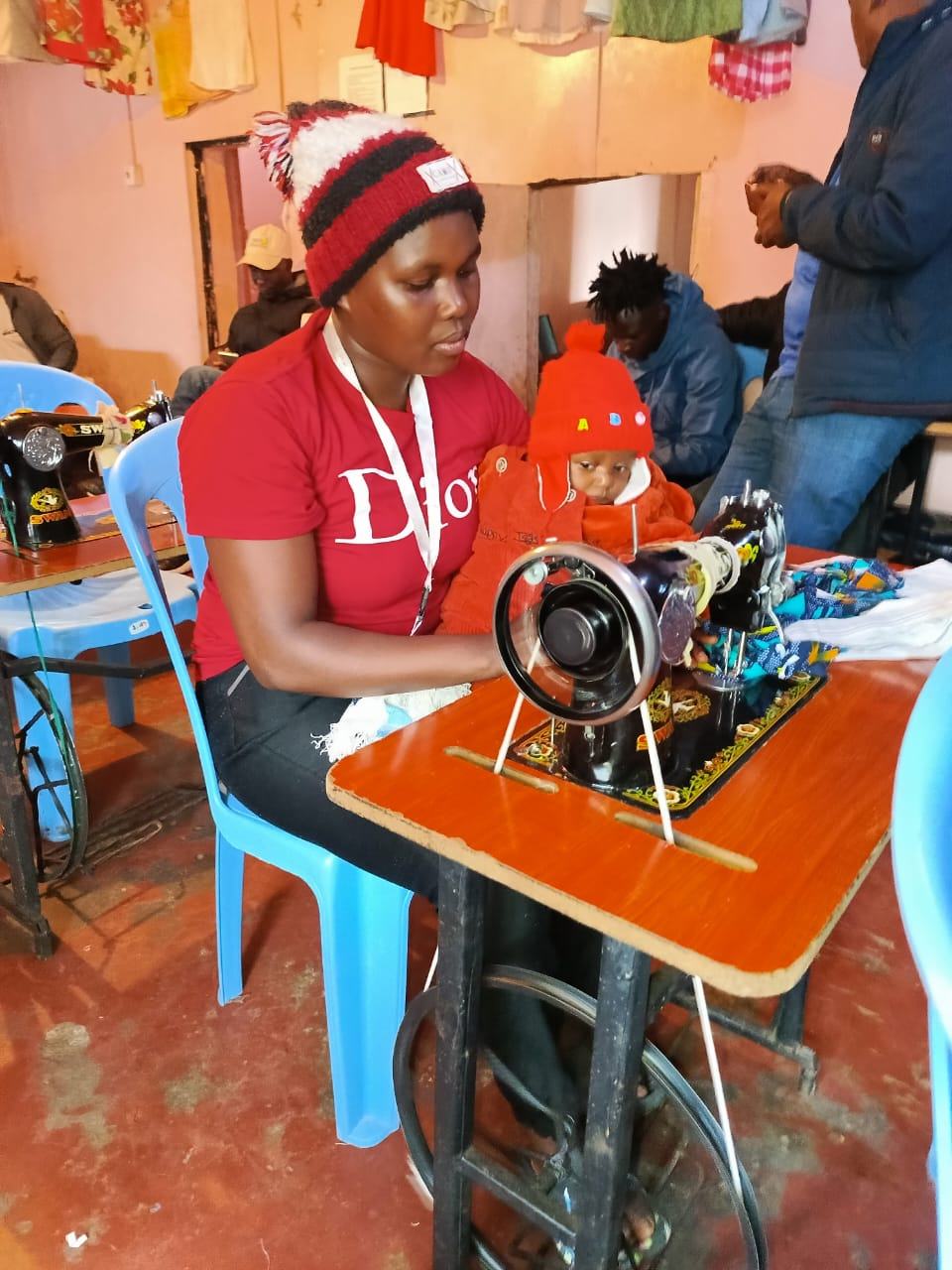 A mother sewing at a machine with her baby beside her