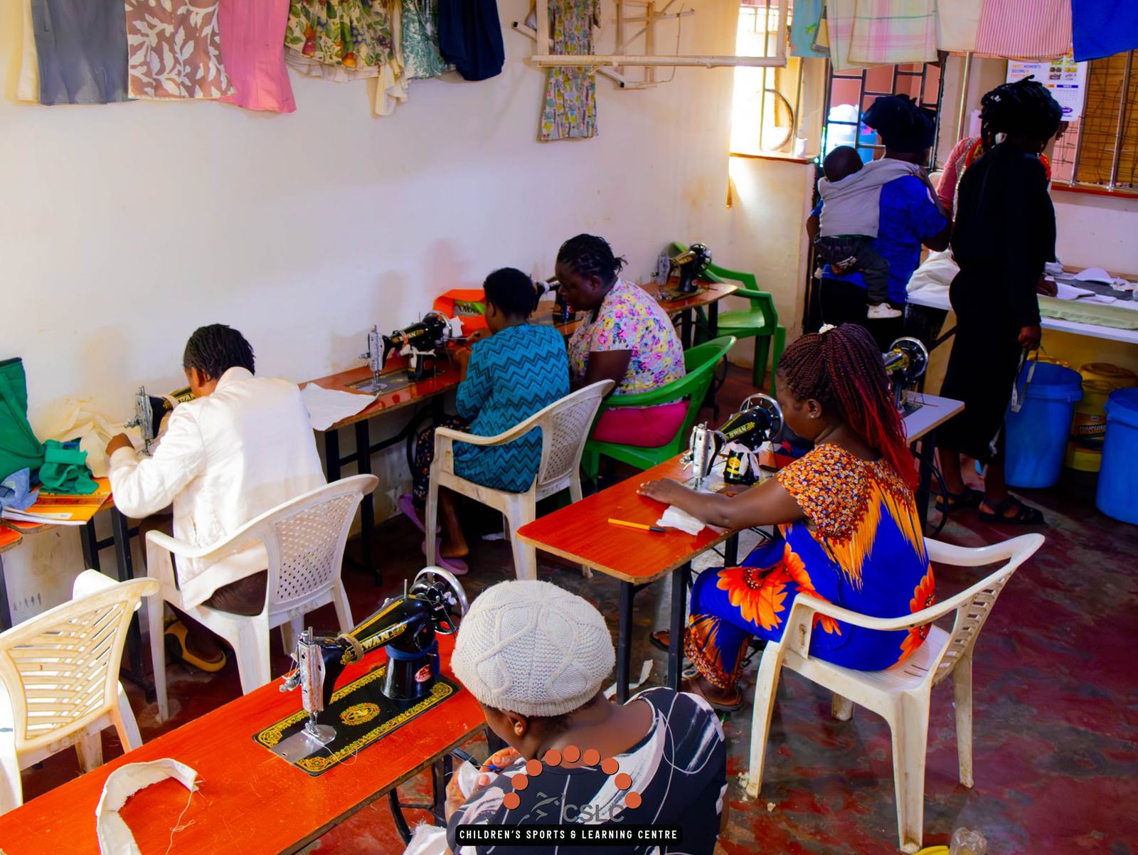 Women learning to sew together at rows of sewing machines